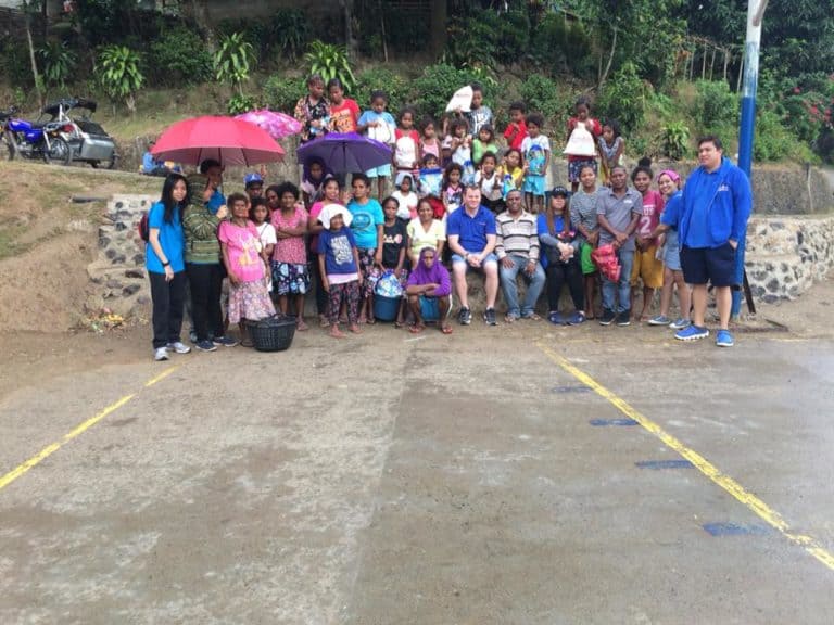 Large community gathering with umbrellas during MyOutDesk Aeta outreach in the Philippines
