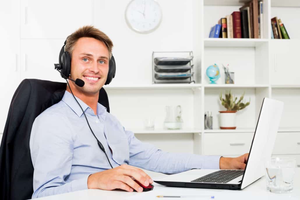 a male virtual assistant smiling at a computer using asana