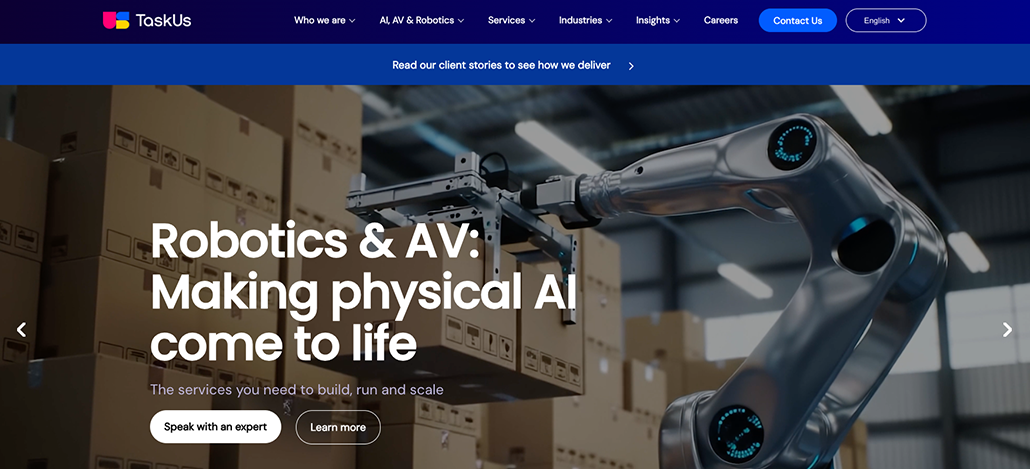 A robotic arm moves a cardboard box in a warehouse. The screen displays the text Robotics & AV: Making physical AI come to life, navigation menus for TaskUs services, and a section answering "What is Customer Service Outsourcing?".