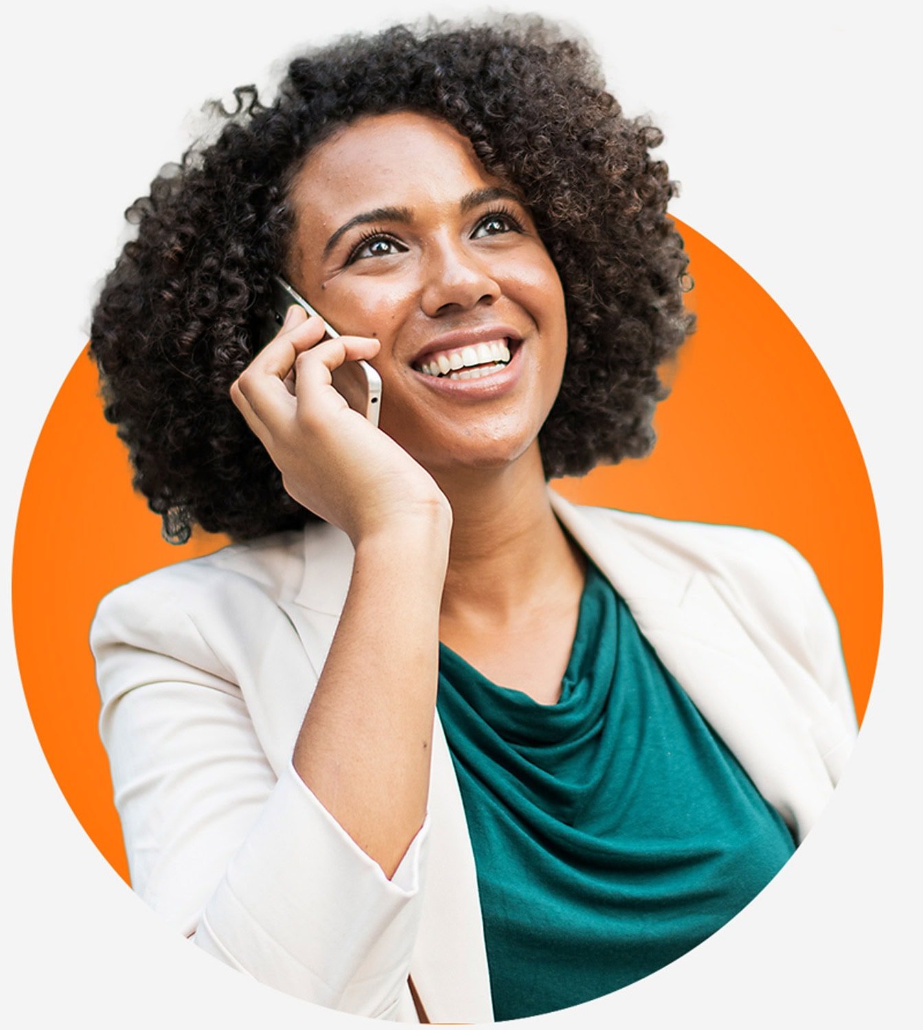myoutdesk-contact-us A woman with curly hair smiles while talking on a smartphone, inviting you to contact us. She wears a teal top and light-colored blazer, set against an orange circle background.