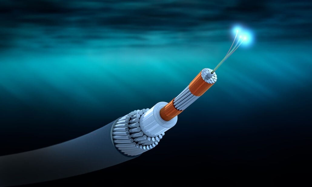 A cross-section of an undersea fiber optic cable with glowing fibers, shown underwater against a blue background. The cable’s internal layers and protective casing are visible, symbolizing North Africa’s growing role as a digital Talent Hub.